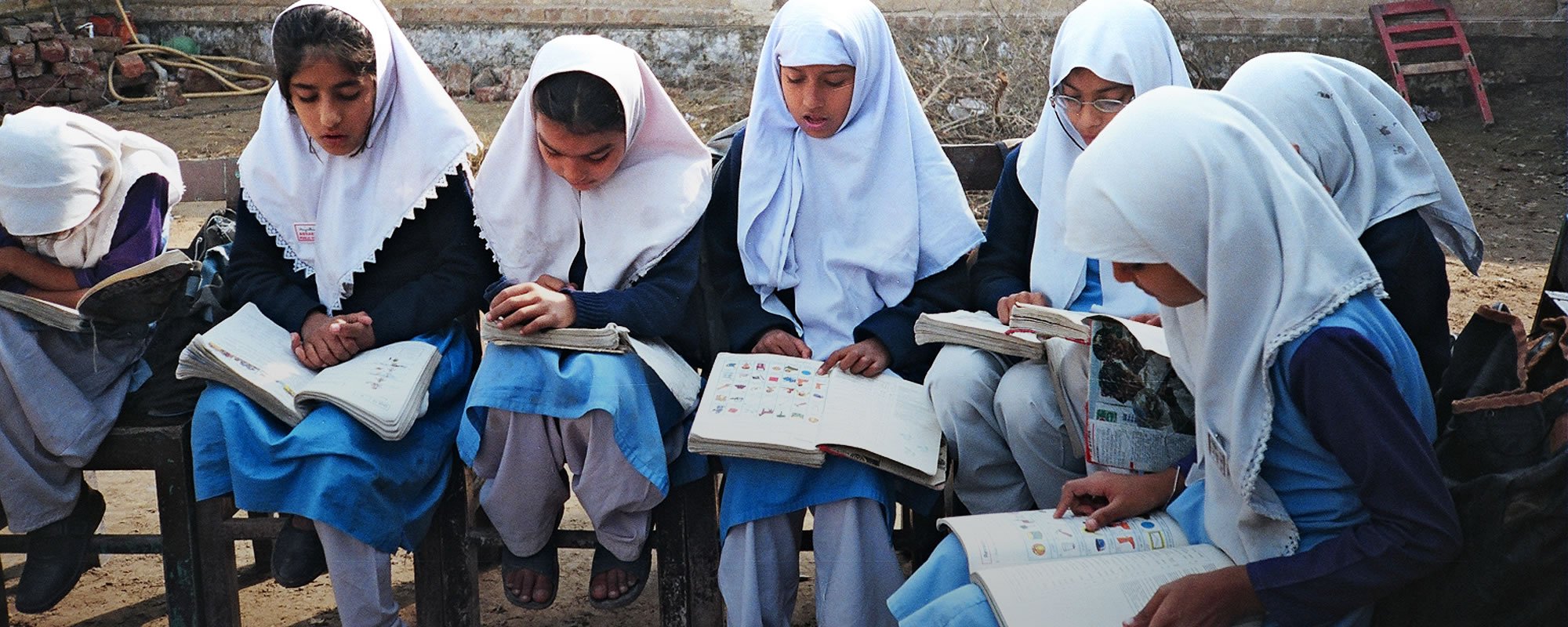 Group of girl students with head coverings studying with workbooks